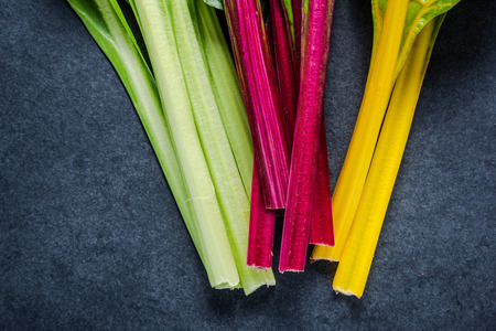 Swiss rainbow chard, vibrant vegetable. Flat lay, from above on dark slate.