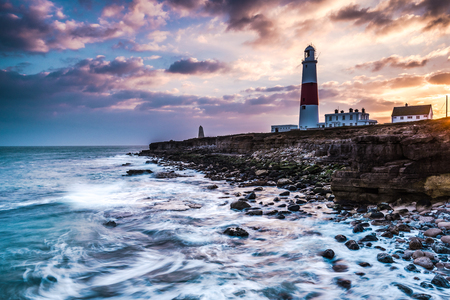 Time lapse sunset on coast with lighthouse on cliffs in Portland, Dorset, UK.の写真素材