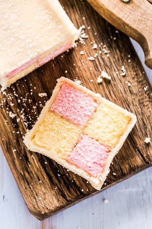 slicing Battenberg homemade sponge cake, on wooden boardの写真素材