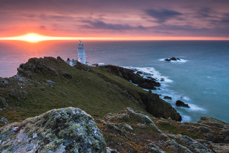 Start Point lighthouse at sunrise in Devon, UK on rocky cliffs.の写真素材