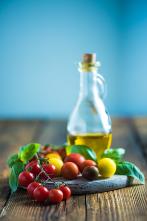 Fresh tomatos, basil and olive oil on wooden table, copy space.の写真素材