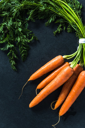 Whole carrots isolated on dark slate flat lay from aboveの写真素材