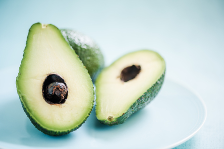 Fresh avocado cut in half, on vibrant blue backgroundの写真素材