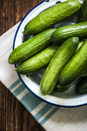 bowl with fresh cucumbers from above on wooden tableの写真素材