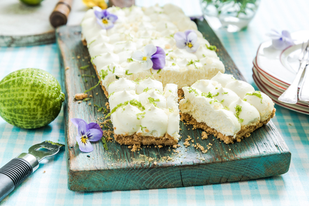 taste of summer, key lime pie with flowers, sliced and served on wooden boardの写真素材
