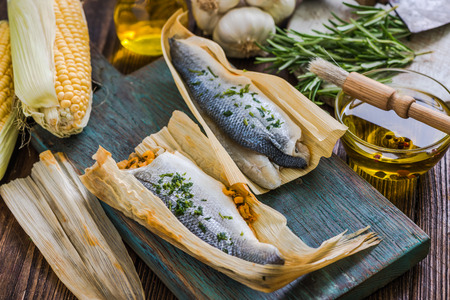 Seabass fish wrapped in corn husk, bbq preparationの写真素材