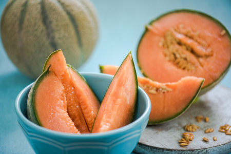 orange melon slices in bowl on wooden boardの写真素材