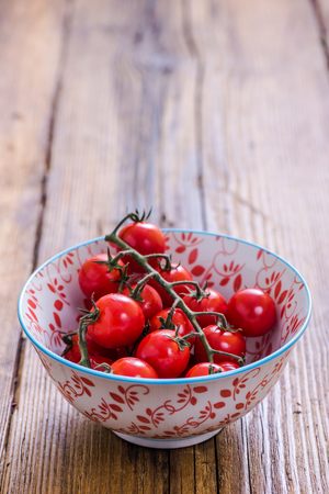 sweet cherry tomatos on wooden table in ceramic bowlの写真素材