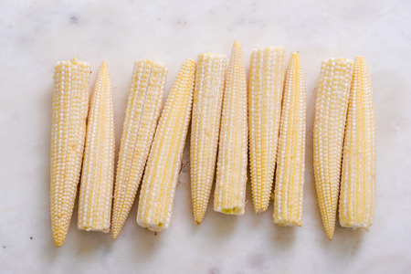 baby corn cob in row on marble boardの写真素材
