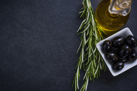 olive oil with olives and herbs on dark slateの写真素材