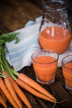 carrot juice in pincher on wooden tableの写真素材