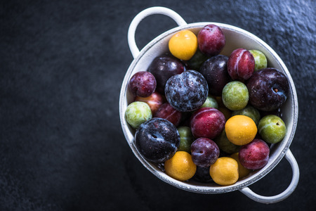 ripe colorful plums from orchand in rustic colanderの写真素材