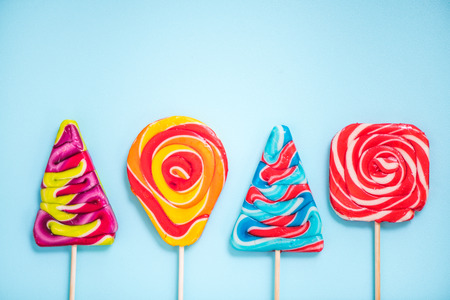 colorful vibrant lollipops , flat lay on blue backgroundの写真素材