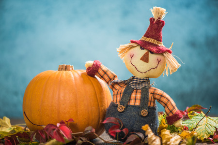 Funny scarecrow holding pumpkin in autumnal backgroundの写真素材