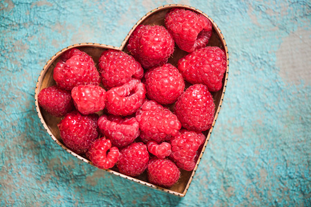 Raspberries in heart shape symbol, love for fruits and healthy living concept