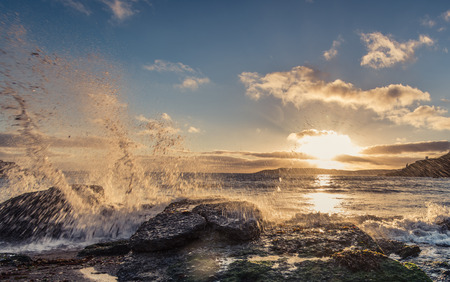 Waves crashing on the rocks at sunset at Wembure Beach in Devon, UKの写真素材