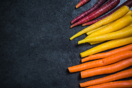 Rainbow carrots border background on dark slateの写真素材