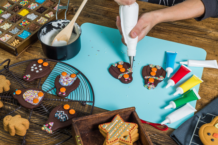 Decorating Christmas pinguins cakes by hand with icing sugarの写真素材