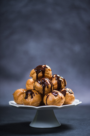 Profiterole eclair stack on platter topped with melted chocolate
