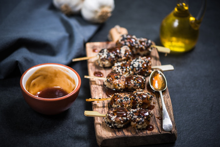 grilled chicken kebabs skewers with sesame and sauce on wooden boardの写真素材