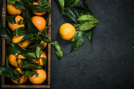 hand picked ripe tangerines in wooden crate with leavesの写真素材