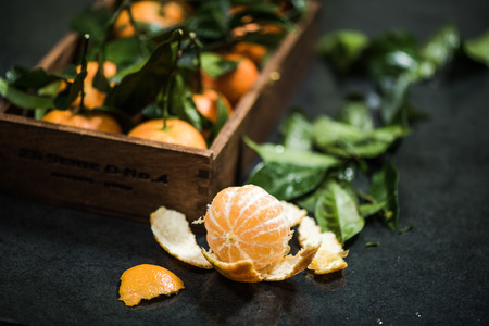 hand picked ripe tangerines in wooden crate with leavesの写真素材