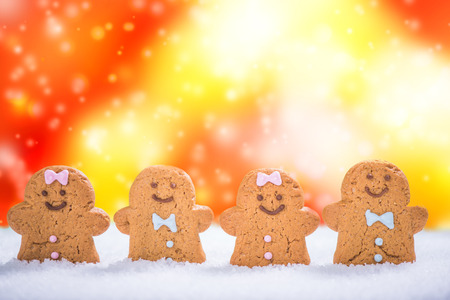 Funny gingerbread kids in snow over festive blured background