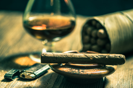 Cuban cigars and glass of alcohol on wooden deskの写真素材