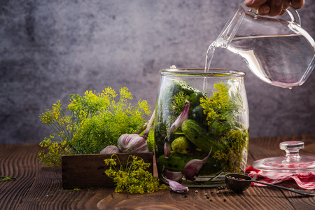 Filling jar with cucumbers for winter pickles on wooden table.の写真素材