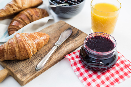Fresh croissant with blueberry marmelade served on wooden boardの写真素材