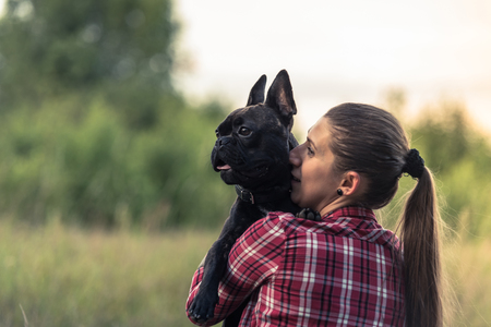 Attractive woman kissing French Bulldog puppy.の写真素材