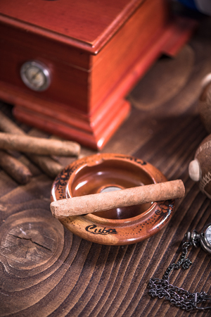 Cuban cigar in ashtray on wooden table, items related to travel to Cuba.の写真素材