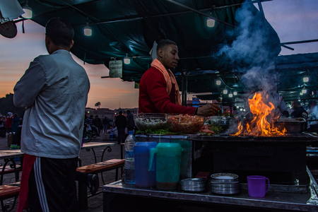 Marrakech,Morocco - January 2018: Chef cooking over open fire gril in Morocco famous Jamaa El Fna marketのeditorial素材
