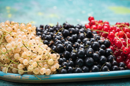 White currant, redcurrant and blackcurrant, on wooden plate.の写真素材
