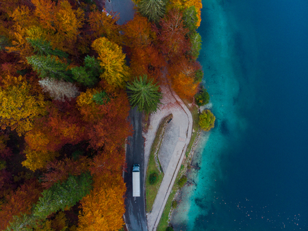 Car drive on road in autumn forest by lake, aerial view.の写真素材