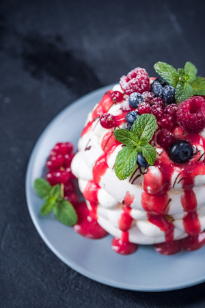 Pavlova with custard and fresh fruits on plate.の写真素材