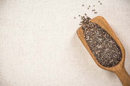 Chia seeds on wooden spoon, superfood. Copy space on kitchen cloth with spotlight.の写真素材