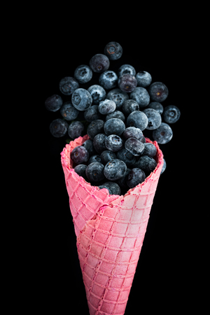 Pink wafer cone with frozen blueberry fruits. Healthy ice cream.の写真素材