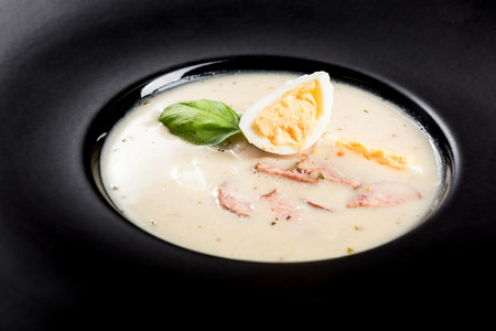 Homemade sour soup served with egg on dark plate.の写真素材