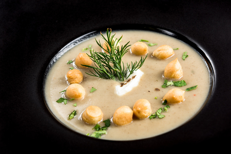 Homemade mushroom cream soup served on dark plate.の写真素材