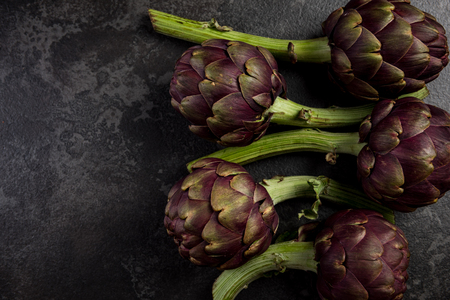 Purple artichokes flowers heads on dark slate.の写真素材
