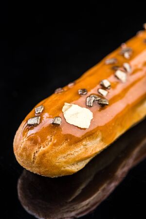 French Artisan Eclair on Black Reflective Background,Copy Space. Patisserie Bakery Product.