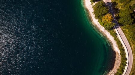 Road and Forest at Lake Edge. Top Down Aerial Drone View .