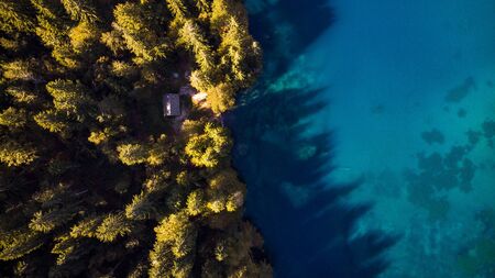 Autumn Forest and Blue Lake Top Down Aerial Drone View. Small Hut in Forest.