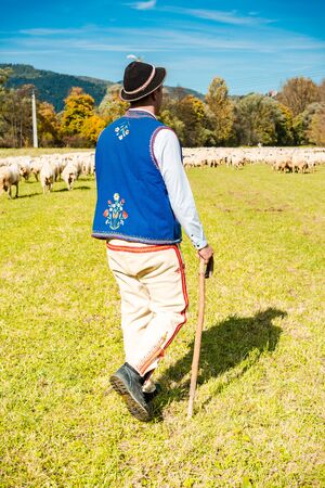 Traditional Polish Highland Shepherd in Regional Clothing at Sheep Pasture.の写真素材