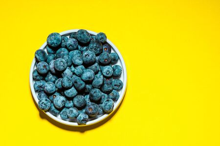 Market Fresh Blueberry on Vibrant Yellow Background. Food Background with Copy Space. Top Viewの写真素材