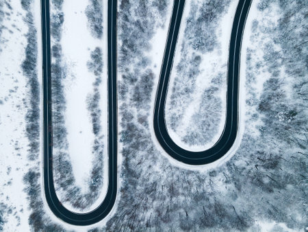 Curvy Windy Road in Snow Covered Forest, Top Down Aerial Drone View.の写真素材