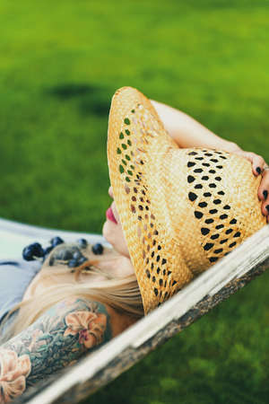 White Woman Relaxing on Hammock in Straw Summer Hat.