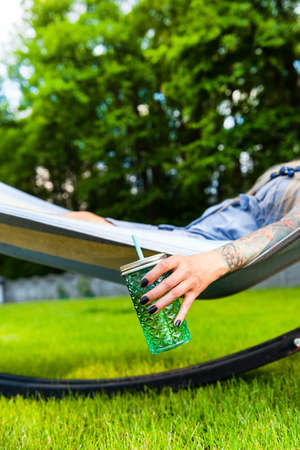 Tattooed Young Woman Relaxing on Hammock in Garden at Summer.の写真素材