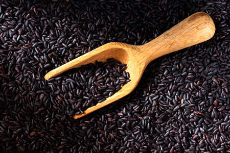 Uncooked Black Rice Grain Background and Wooden Spoon.の写真素材